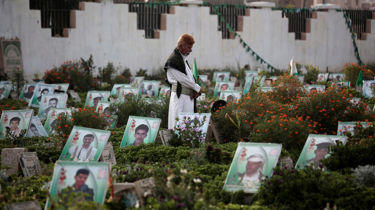 A man offers prayers Monday in Sanaa, Yeman, at the portrait-adorned grave of a relative killed in the ongoing conflict.