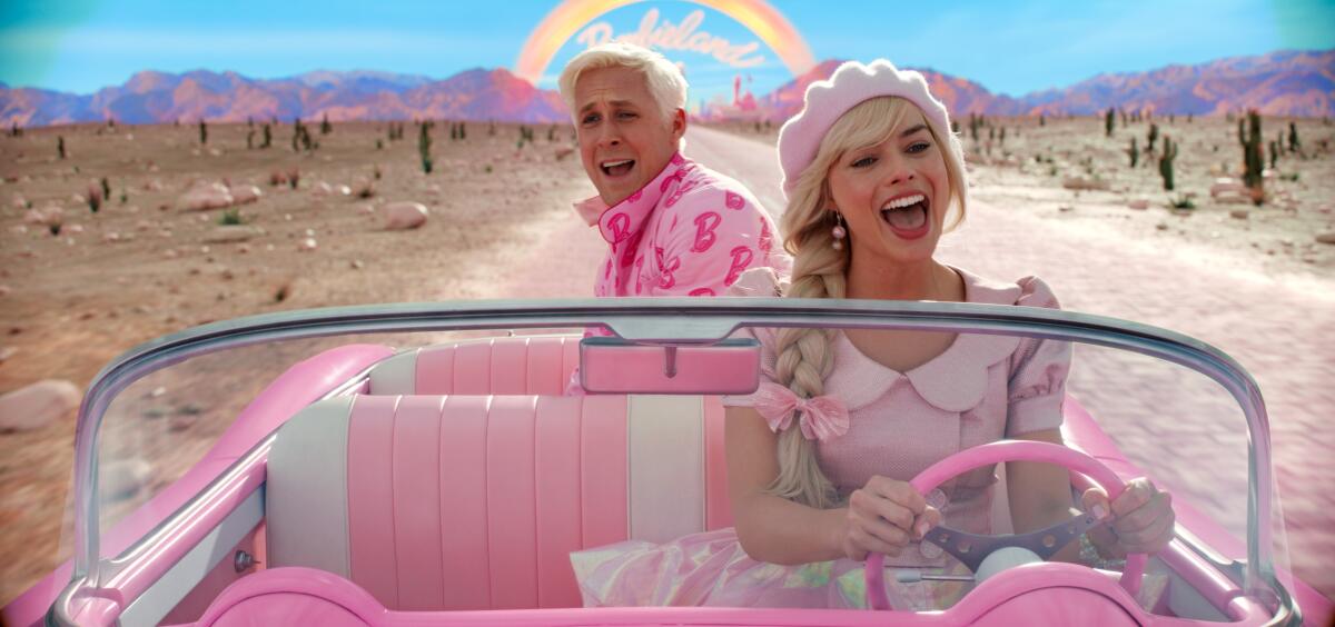 Ryan Gosling as Ken and Margot Robbie as Barbie drive through the desert in a small pink car.
