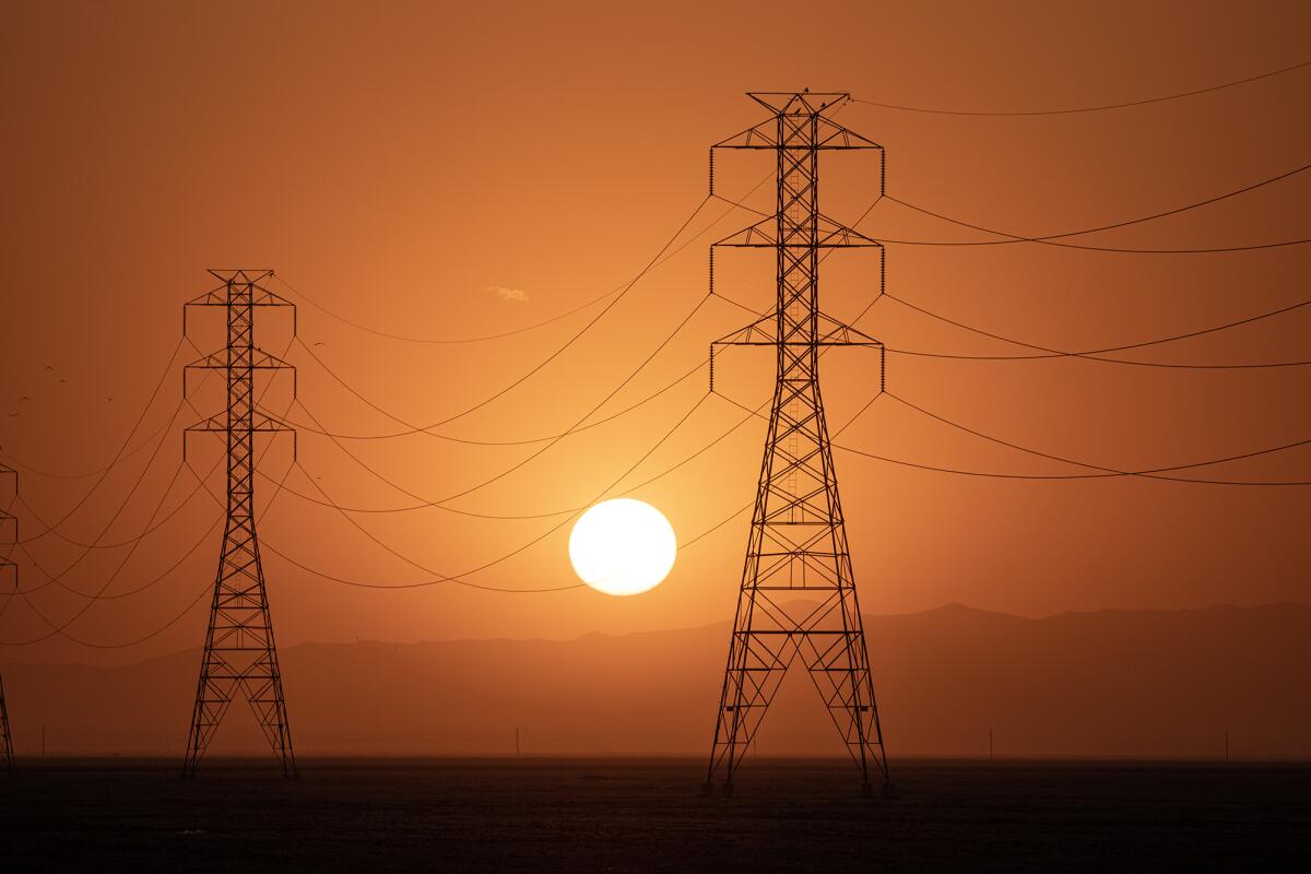 El sol se pone detrás de una hilera de torres eléctricas en el condado de Fresno el 6 de septiembre de 2022