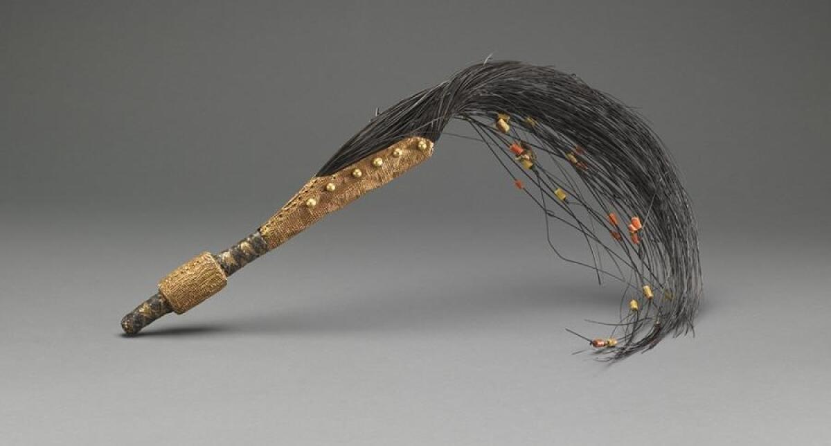An elephant tail whisk with gold details and beads.