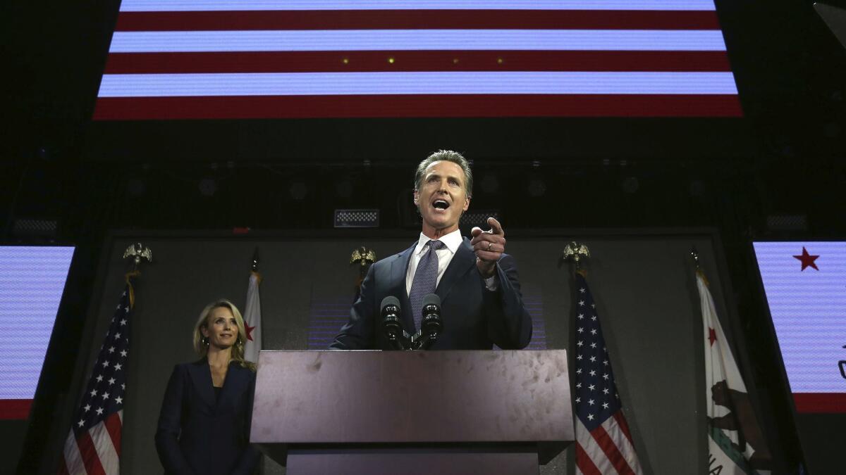 Gov.-elect Gavin Newsom addresses the crowd at an election-night party on Nov. 6 as his wife, Jennifer Siebel Newsom, left, looks on.