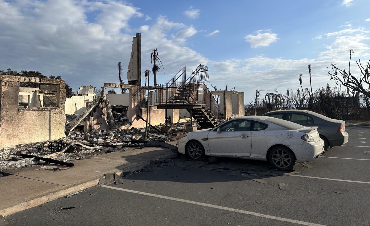Cars parked in front of the charred ruins of an apartment building