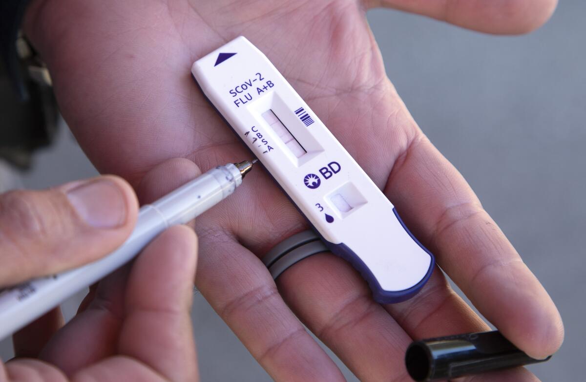 Components of a home coronavirus and flu test kit in a person's hands