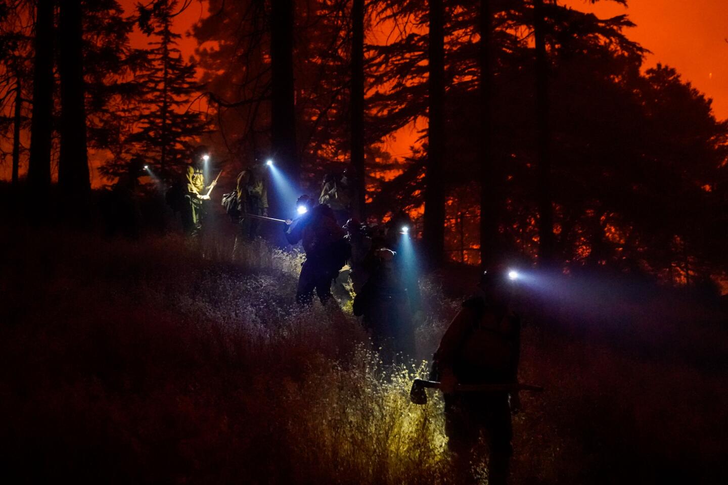 Firefighters with headlamps and tools battle the Creek fire in Big Creek, Calif.
