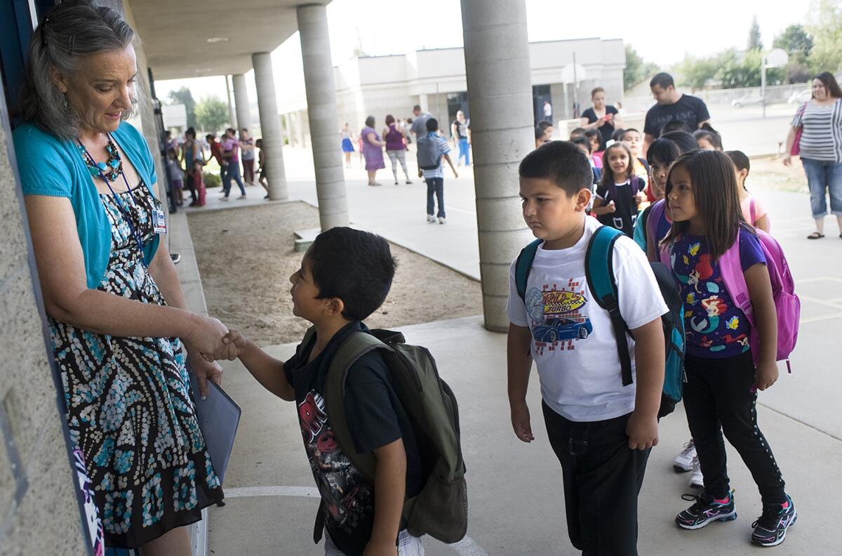 First-grade teacher Gail Lemmen, left, welcomes each student to the first day of the school on Monday, Aug. 11, 2014 at Los Robles Elementary School in Porterville, Calif.