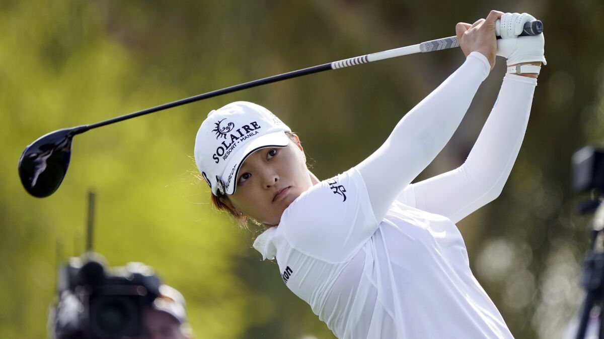Jin Young Ko holds up a golf club.