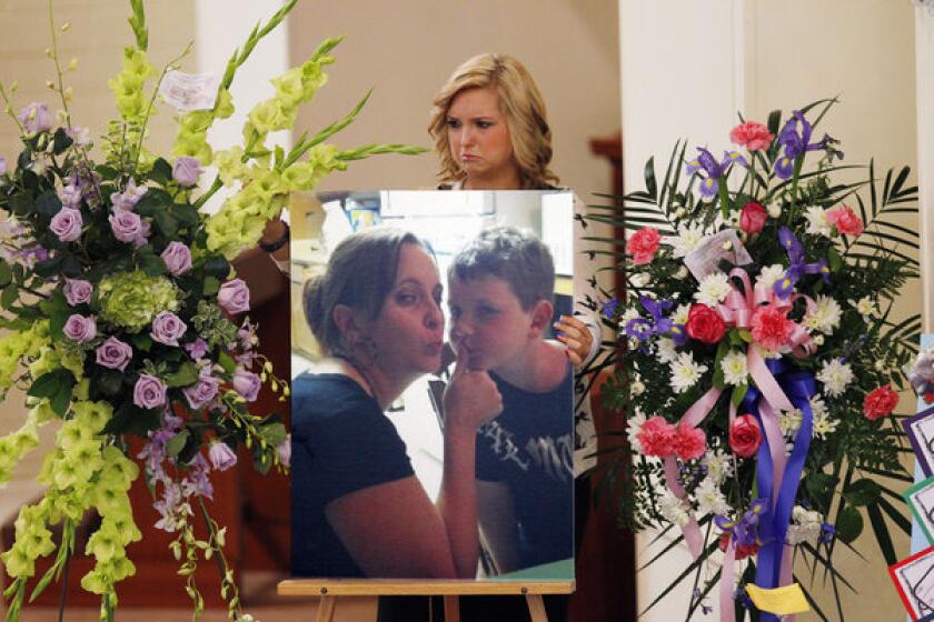 Kidnap victim Hannah Anderson positions a photo of her slain mother, Christina Anderson, and brother, Ethan Anderson, on an easel at an Aug. 24 memorial service.