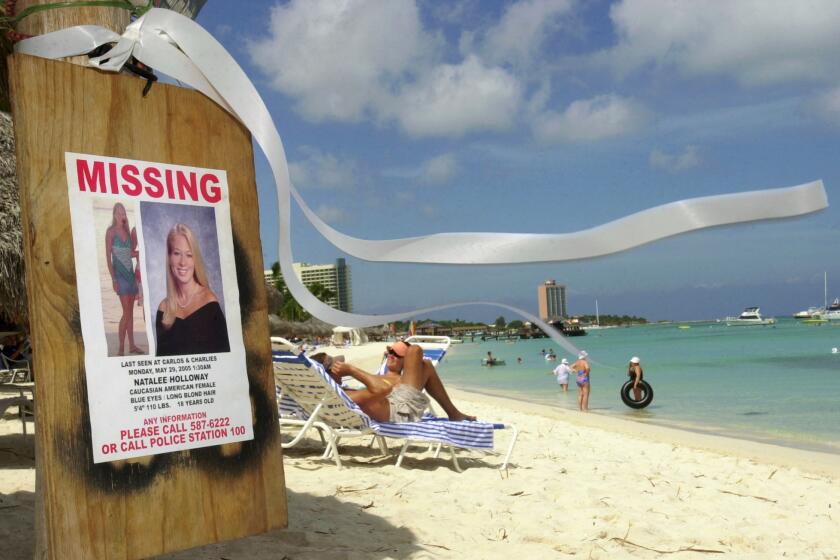 FILE - This June 10, 2005 file photo shows a missing poster for Natalee Holloway, a high school graduate of Mountain Brook, Alabama who disappeared while on a graduation trip to Aruba on May 30, 2005, on Palm Beach where tourists sunbathe in Aruba. Aruba prosecutors said Wednesday, May 20, 2015 a tip about the potential location of Holloway's body turned out to be false after spending weeks investigating the claim in the unsolved, decade-long disappearance of the U.S. teen. (AP Photo/Leslie Mazoch, File)