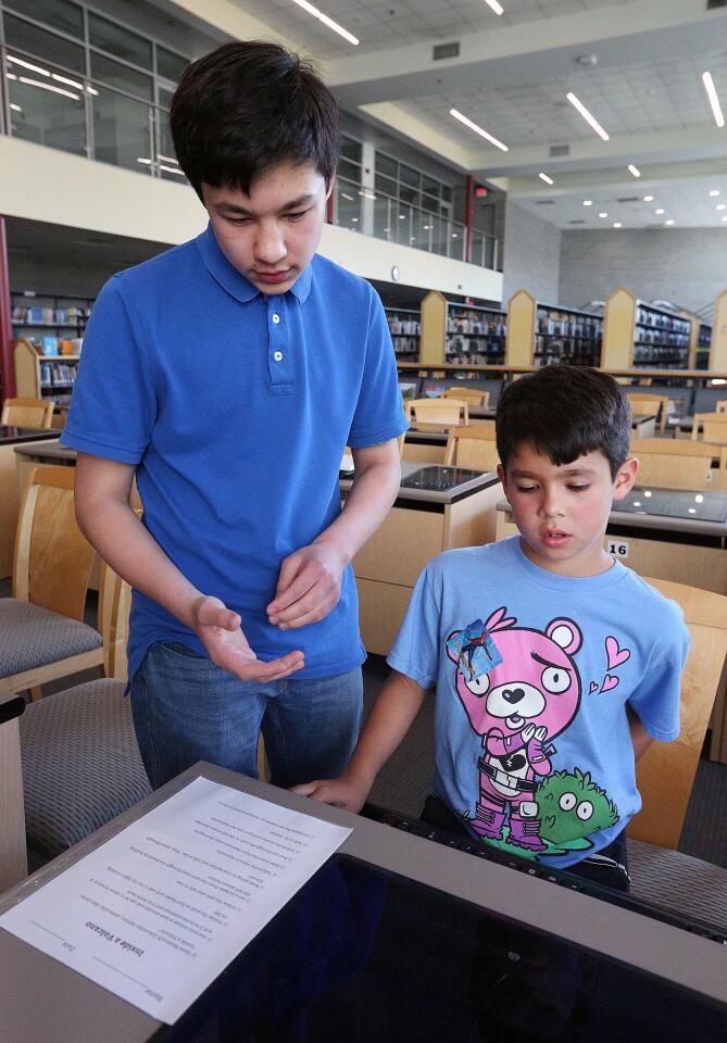 La Canada High School freshman Devyn Oh helps Hudson Ananian, 7, of La Canada, learn a little bit about Minecraft: Education Edition at a Minecraft Expo, hosted by Oh who is using the expo as a project for Eagle Scout at La Canada High School on Friday, April 19, 2019. Oh is introducing a Minecraft: Education Edition with hopes of introducing primary education teachers to the benefits of using the online game as a teaching tool.