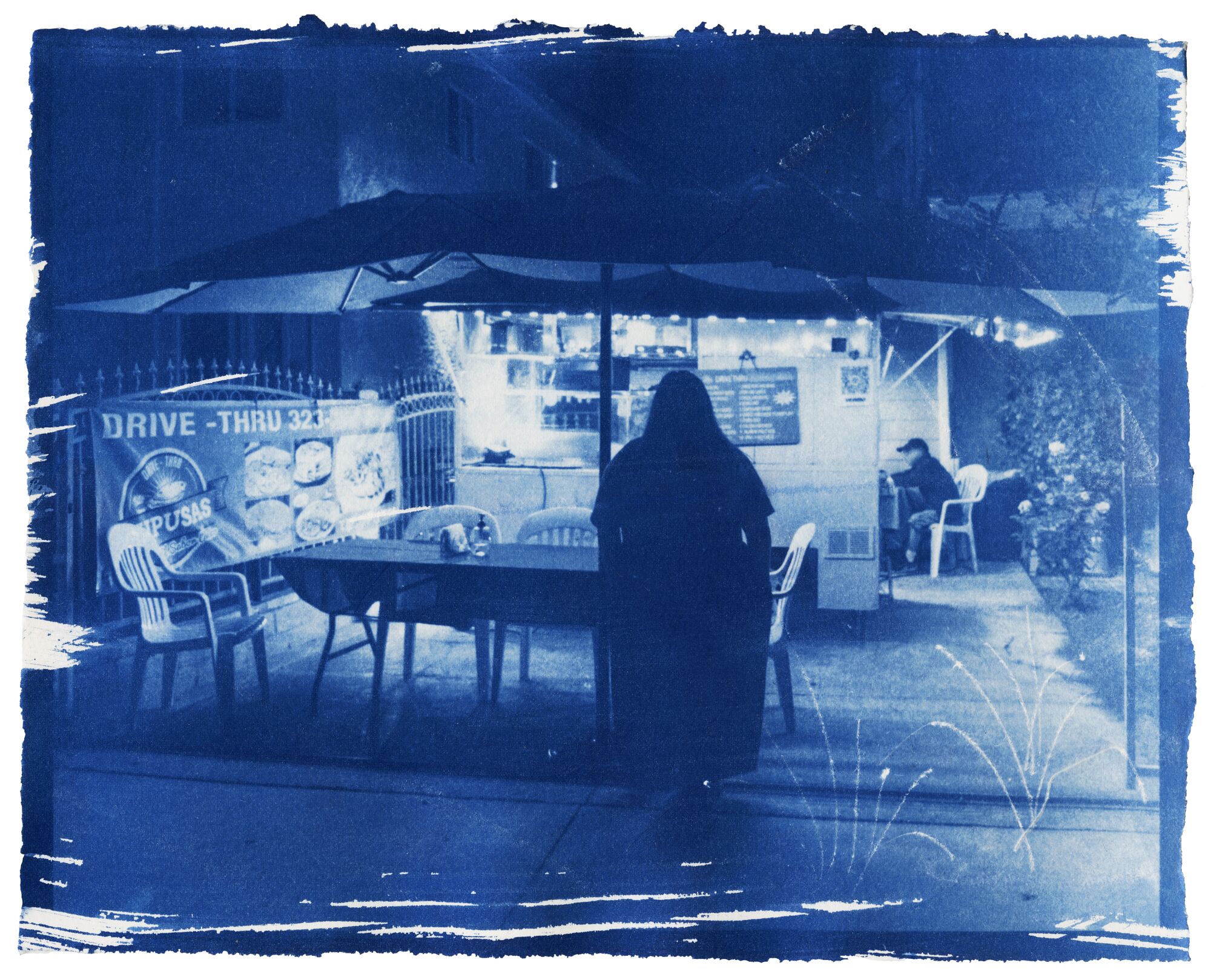 A cyanotype print of waiting pupusas scrambled on a Los Angeles road