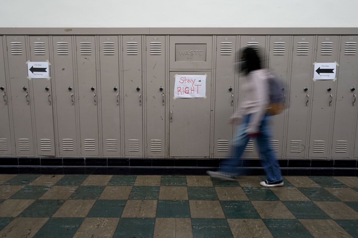 A student walks between classes at Wyandotte High School in Kansas City, Kan., on the first day of in-person learning Wednesday, March 30, 2021. The school, like other schools nationwide, has made extra efforts to keep kids at risk of dropping out engaged as classes went virtual due to the pandemic. (AP Photo/Charlie Riedel)