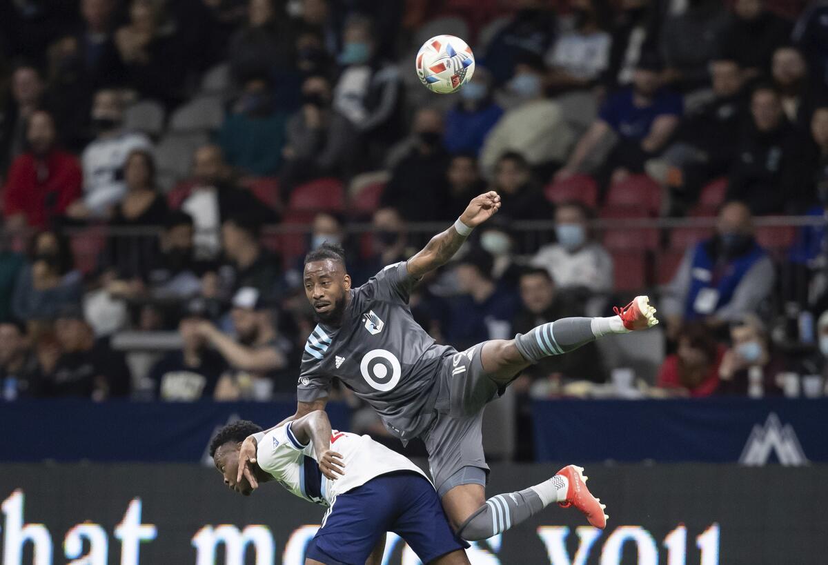 Minnesota United's Romain Metanire, top, falls on Vancouver Whitecaps' Javain Brown as they vie for the ball during the first half of a MLS soccer game, Wednesday, Oct. 27, 2021 in Vancouver, British, Columbia. (Darryl Dyck/The Canadian Press via AP)