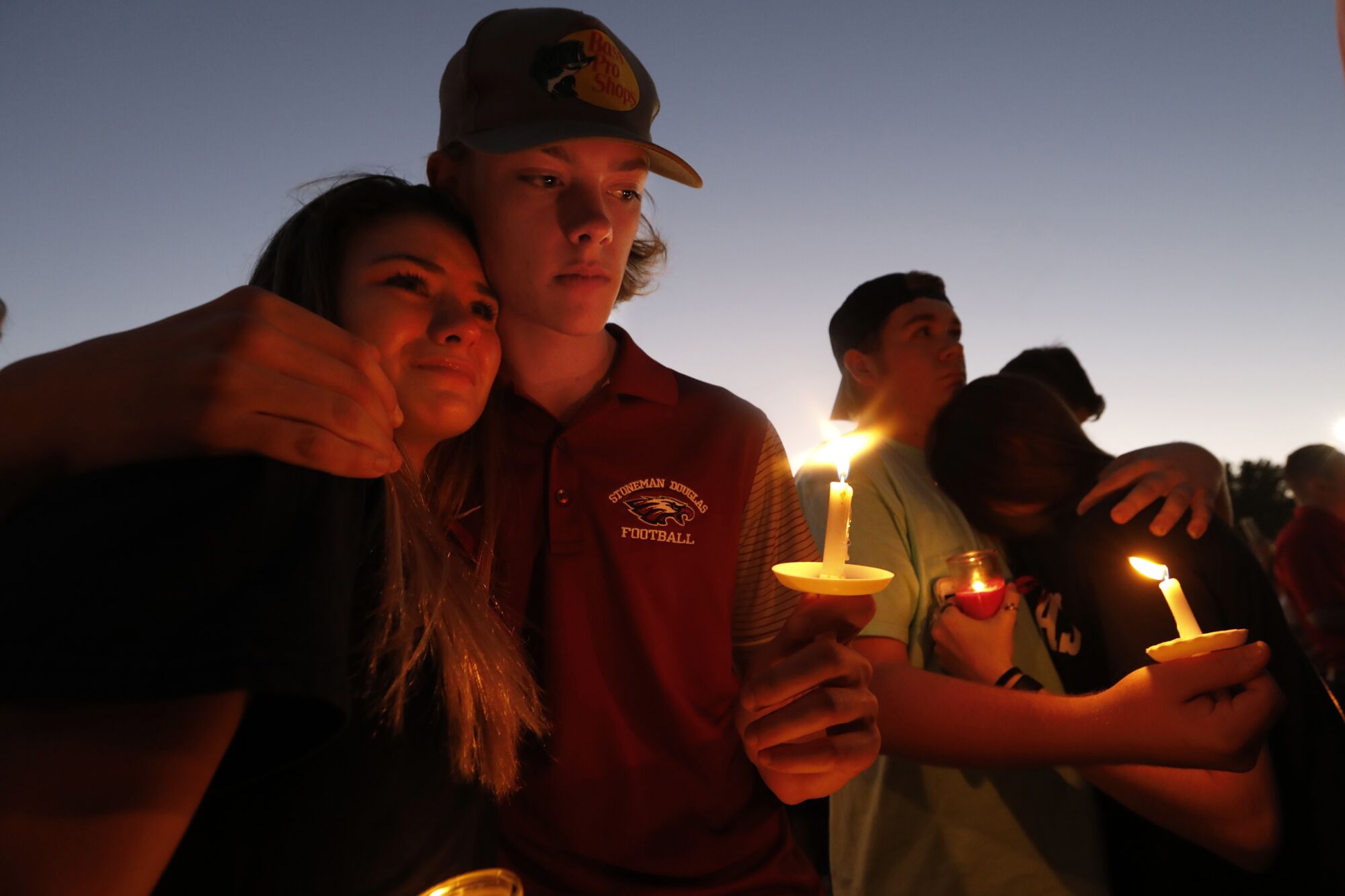 People embrace at a candlelight vigil.