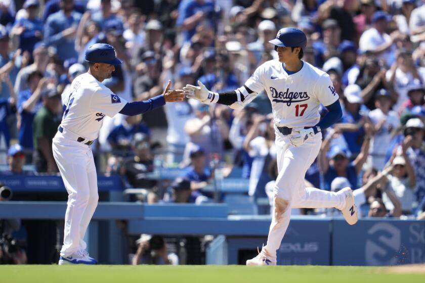 El bateador designado de los Dodgers de Los ngeles Shohei Ohtani celebra con el entrenador de tercera base Dino Ebel su jonrón en la octava ante los Bravos de Atlanta el domingo 5 de mayo del 2024. (AP Foto/Ashley Landis)