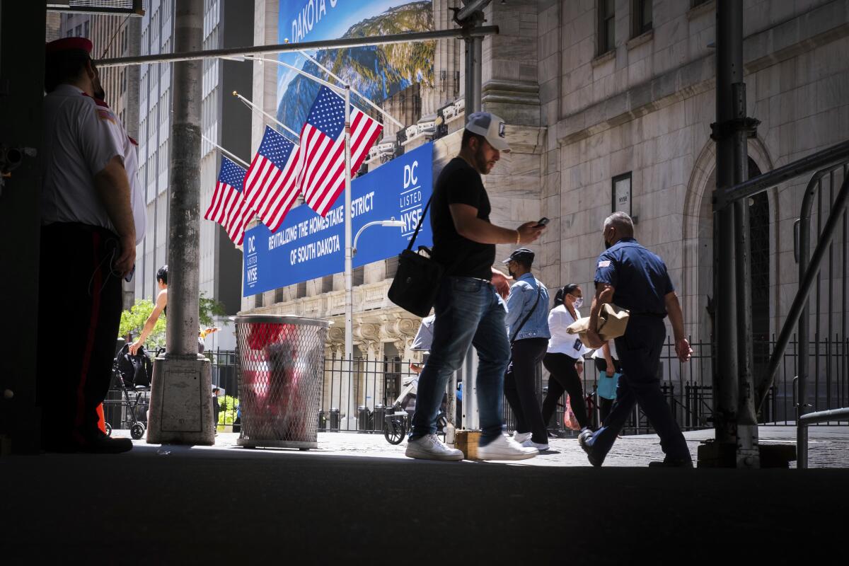 Peatones caminando en los alrededores de la Bolsa de Valores de Nueva York, al fondo