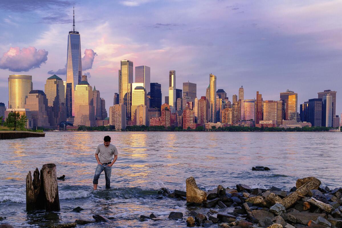 Man wading in canal with Manhattan skyline behind him