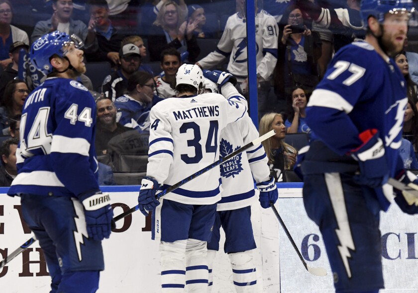 Toronto Maple Leafs center Auston Matthews (34) congratulates right wing Mitchell Marner (16) after Marner's third period goal during an NHL hockey game against the Tampa Bay Lightning, Monday, April 4, 2022, in Tampa, Fla. (AP Photo/Jason Behnken)