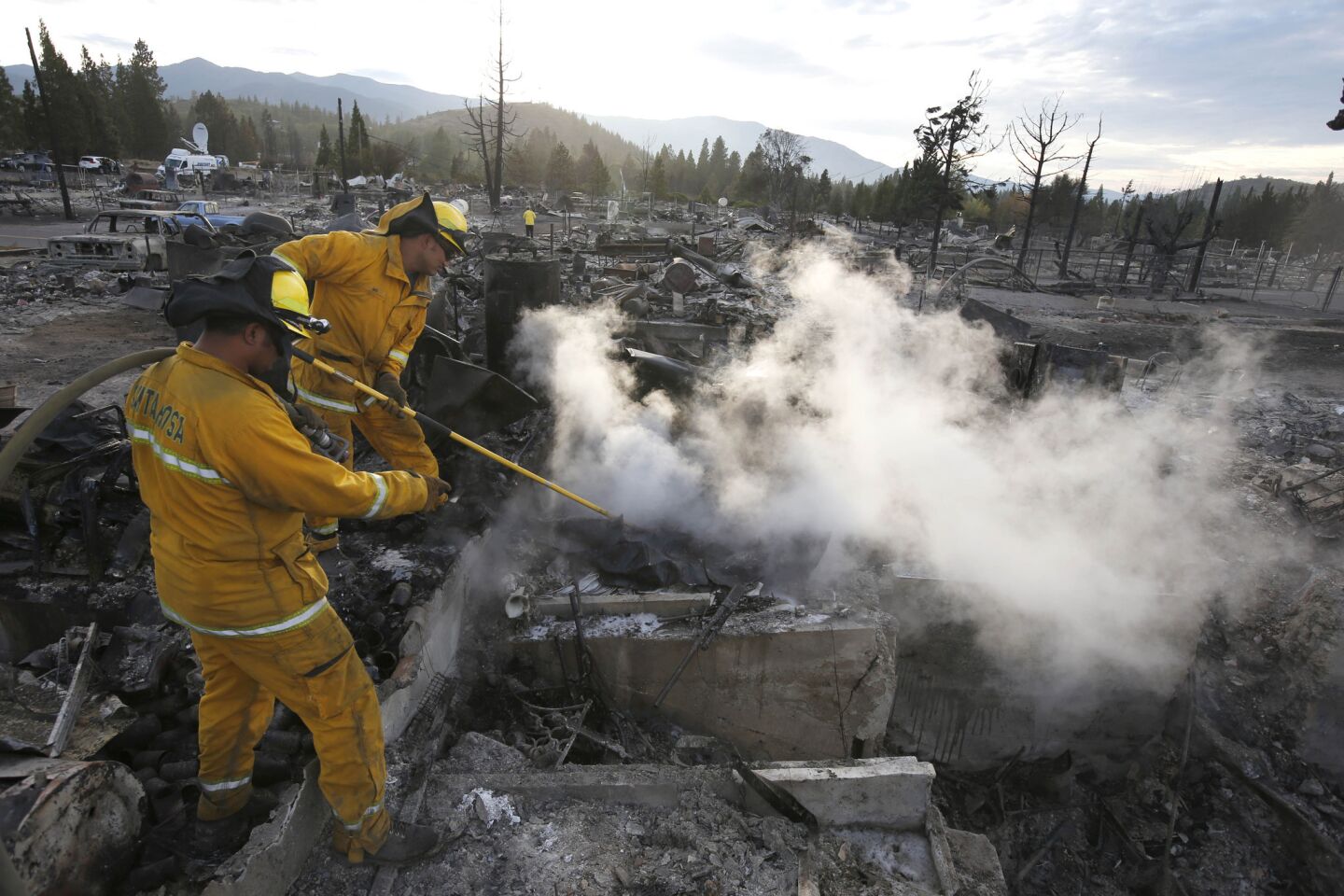 Firefighters put out hotspots at a still smoldering home in a neighborhood destroyed by a devastating fire that rage through Weed, Calif., destroying 150 buildings.