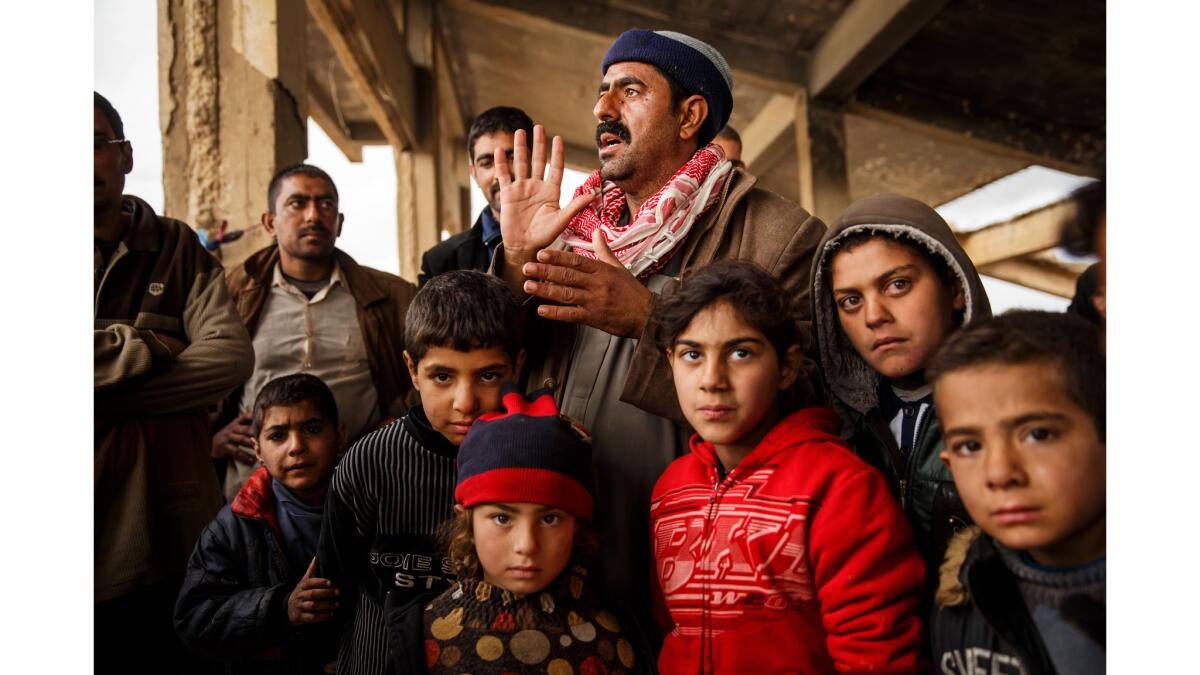 Samir Taha Tahsin, with family members and friends, lives under the concrete ruins of a soccer stadium outside a United Nations camp in Hamam Alil, Iraq.