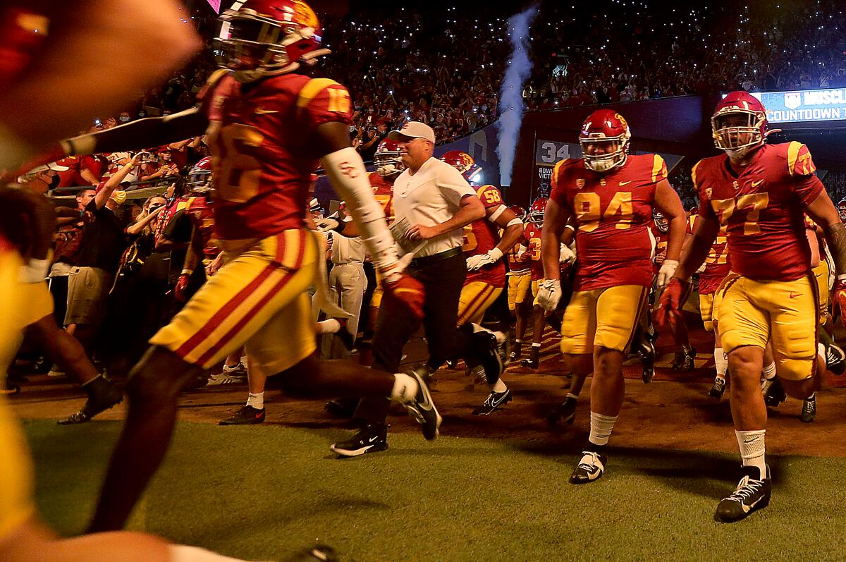 USC coach Clay Helton runs onto the field at the Coliseum with his players before losing to Stanford on Saturday.
