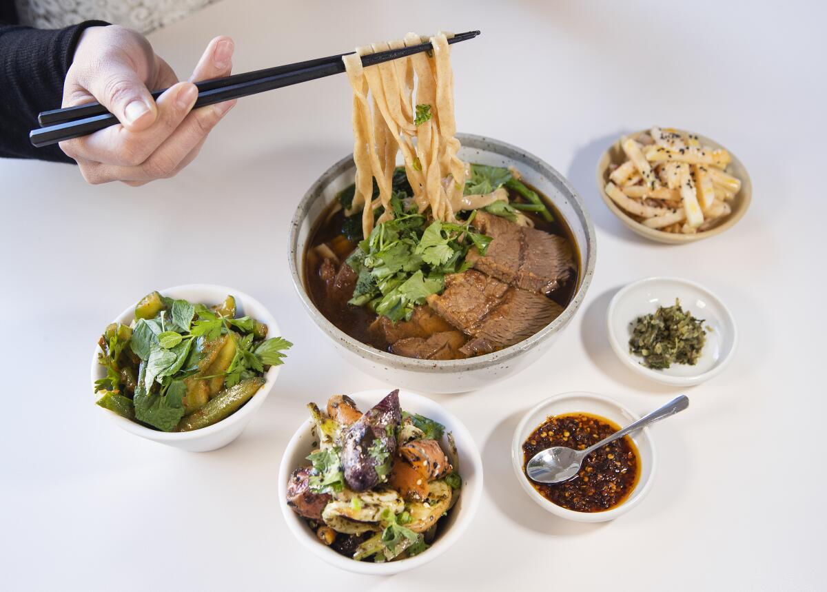 Beef noodle soup, with condiments and vegetable side dishes, at Yang's Kitchen.