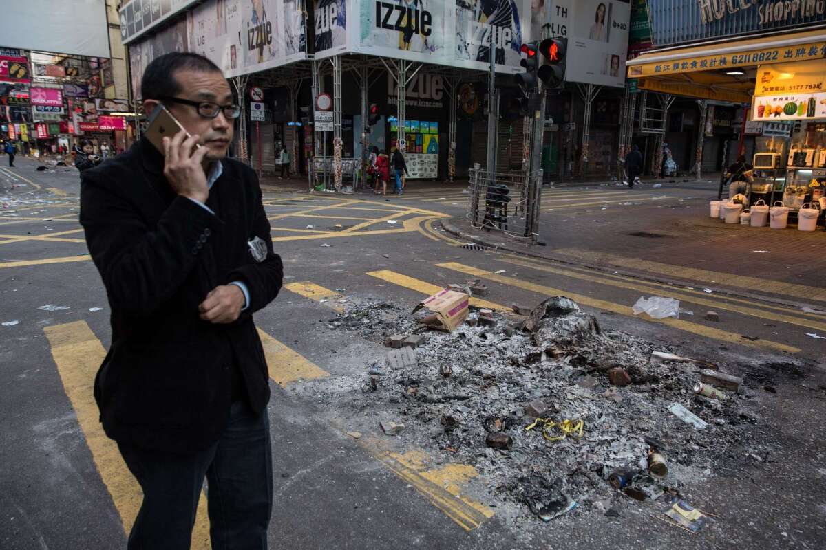 A man walks past burned debris after overnight clashes between protesters and police in the Mong Kok area of Hong Kong.