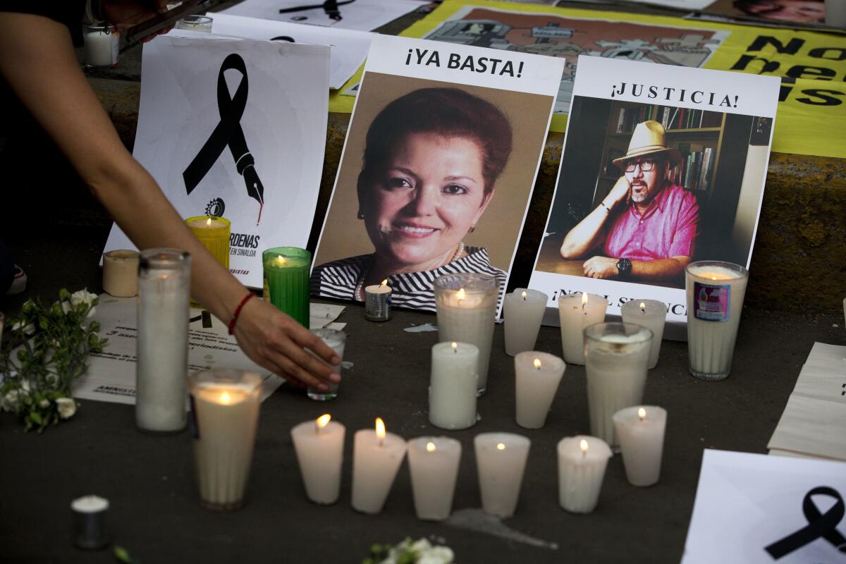   una mujer coloca una vela frente a las fotografías de los periodistas asesinados Miroslava Breach