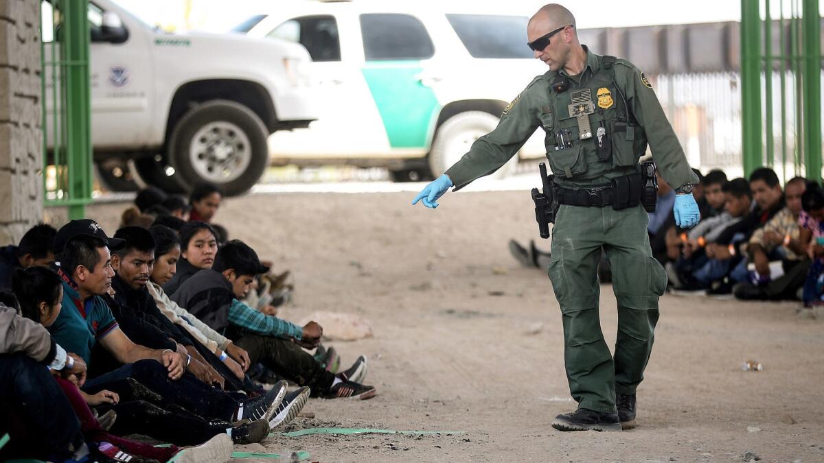A U.S. Border Patrol agent with migrants being detained after crossing the border May 19 in El Paso.