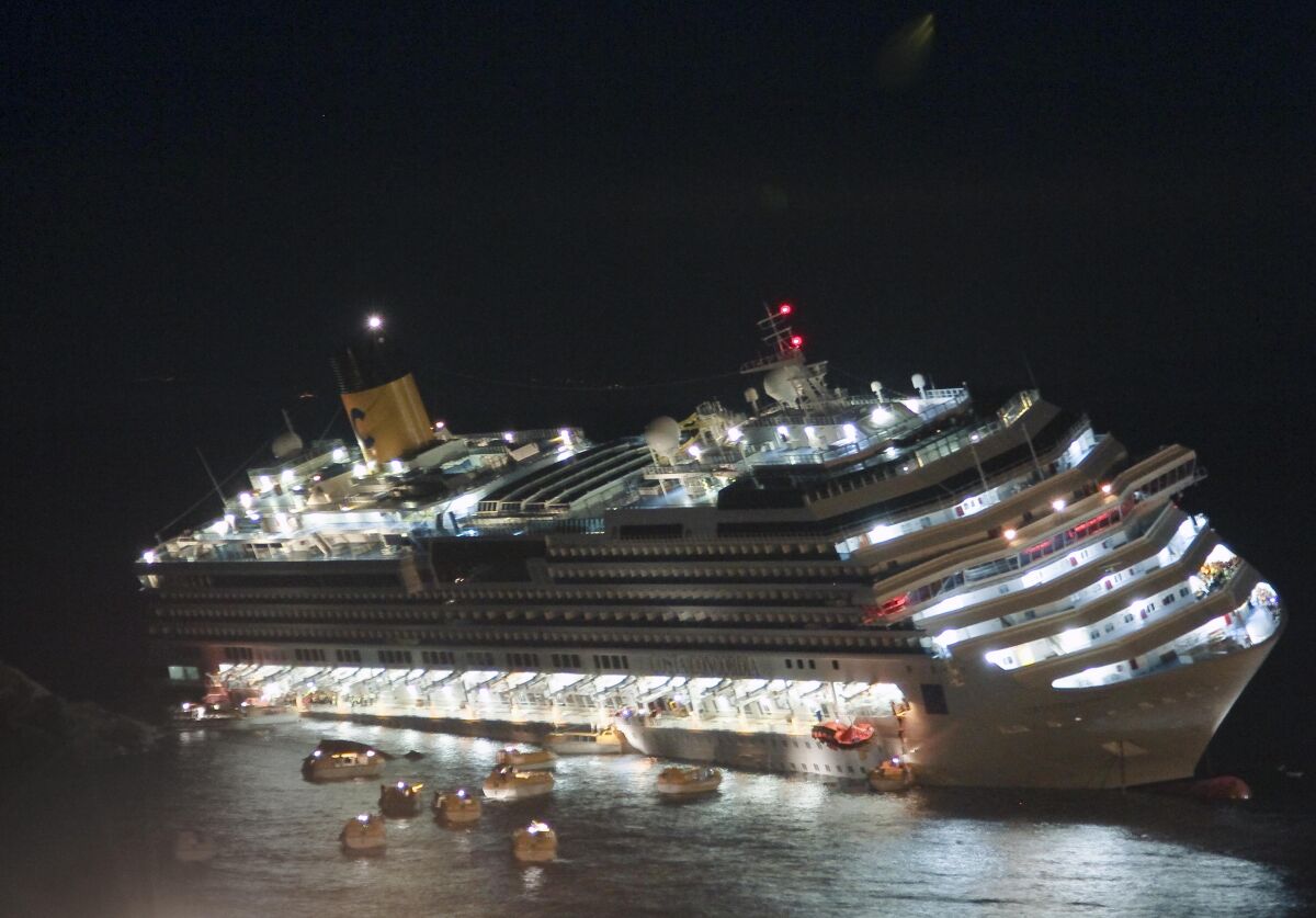 FILE — The luxury cruise ship Costa Concordia lays on its starboard side after it ran aground off the coast of the Isola del Giglio island, Italy on Jan. 13, 2012. Italy is marking the 10th anniversary of the Concordia disaster with a daylong commemoration, honoring the 32 people who died but also the extraordinary response by the residents of Giglio who took in the 4,200 passengers and crew from the ship on that rainy Friday night and then lived with the Concordia carcass for another two years before it was hauled away for scrap. (AP Photo/Giuseppe Modesti)