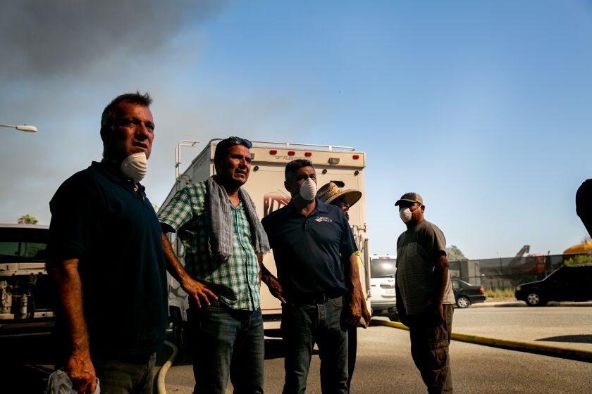 Francisco Ramírez (i) y Saúl Moreno (d) junto a parte del personal observan el incendio registrado en su propiedad el 1 de agosto de 2019 en Otay Mesa