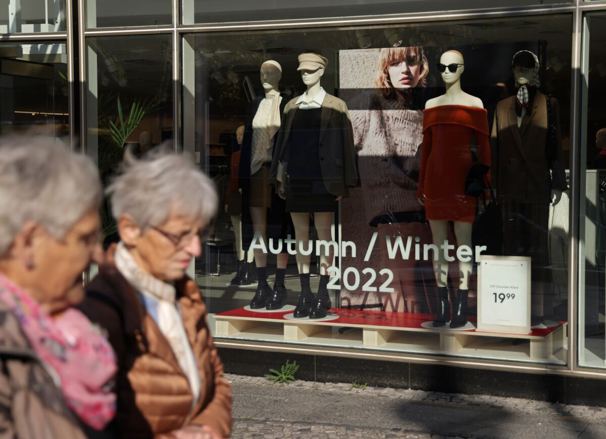 Two women walk past a clothing store
