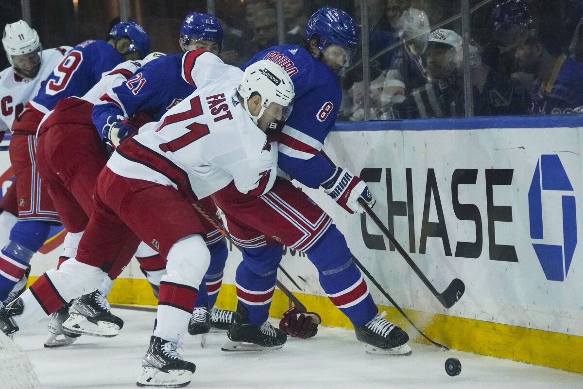 Carolina Hurricanes right wing Jesper Fast (71) and New York Rangers defenseman Jacob Trouba (8) goes for a loose puck during first period of an NHL hockey game, Tuesday, April 12, 2022, in New York. (AP Photo/Bebeto Matthews)