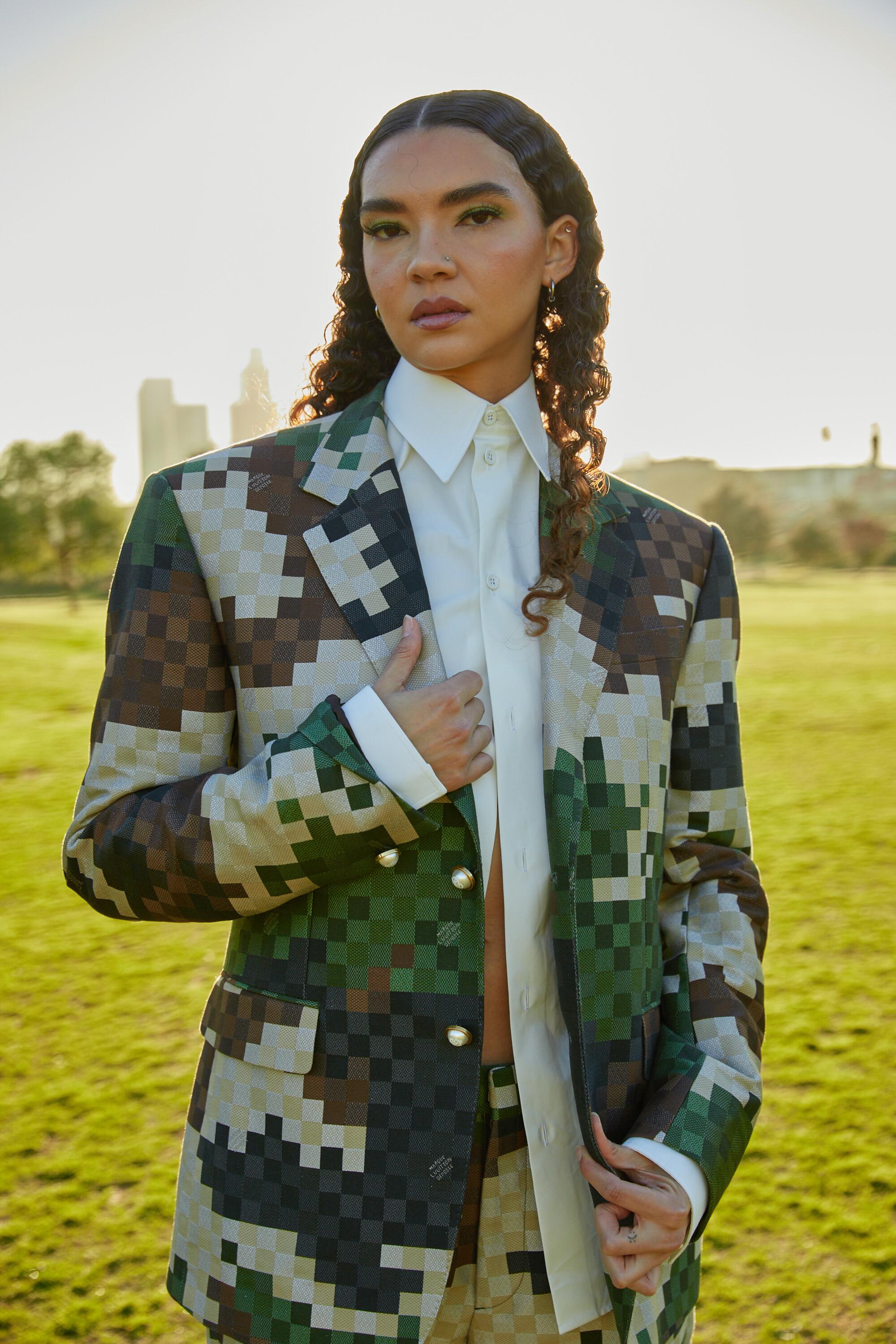 A model wears a pixelated Louis Vuitton jacket in a park.