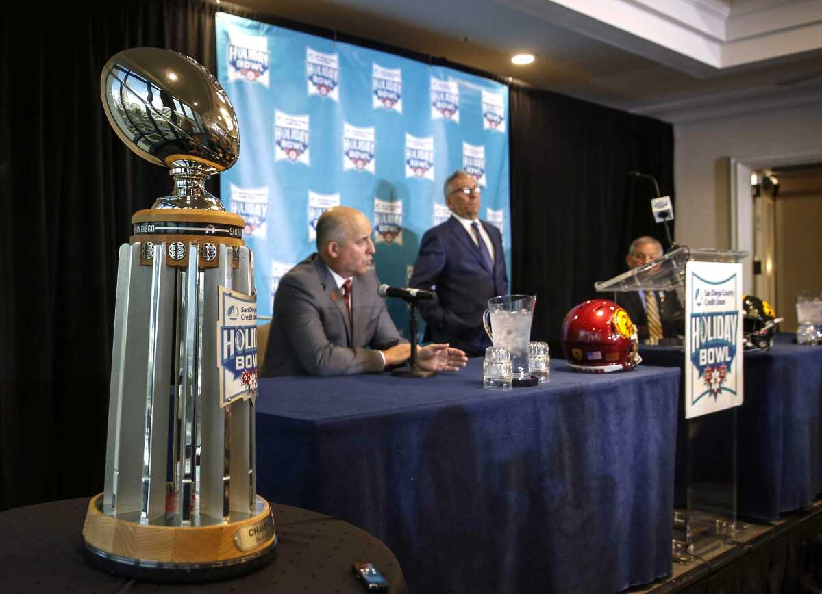 With the Holiday Bowl trophy off to the side, USC coach Clay Helton, left, and Iowa coach Kirk Ferentz, right, speak to the media on Thursday in San Diego.