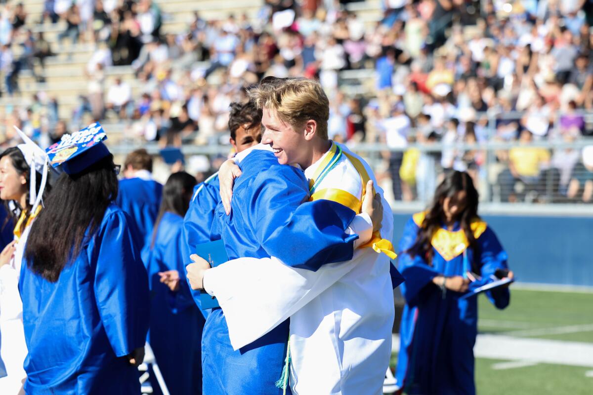 Fountain Valley graduates share a hug at a commencement ceremony on Wednesday at Orange Coast College.