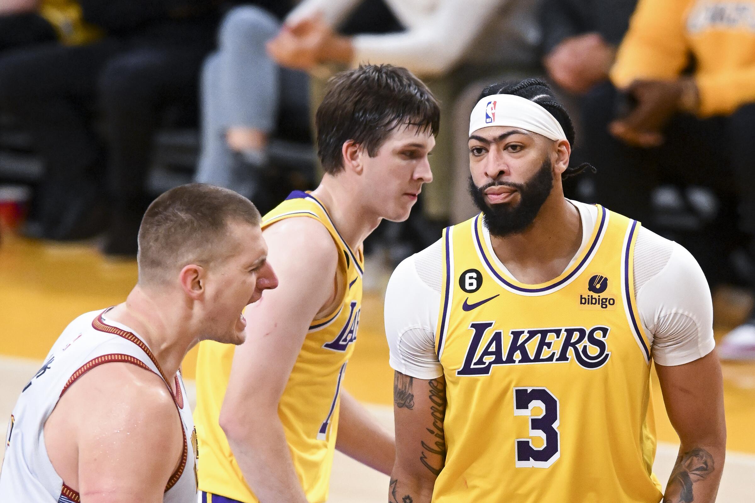 Denver Nuggets center Nikola Jokic celebrates in front of Lakers guard Austin Reaves and forward Anthony Davis.