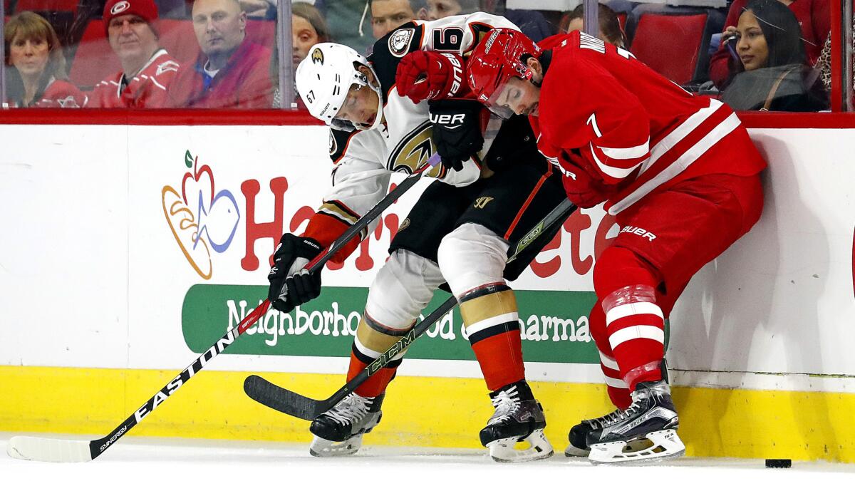 Ducks center Rickard Rakell and Hurricanes defenseman Ryan Murphy (7) battle for the puck along the boards during their game Thursday night.