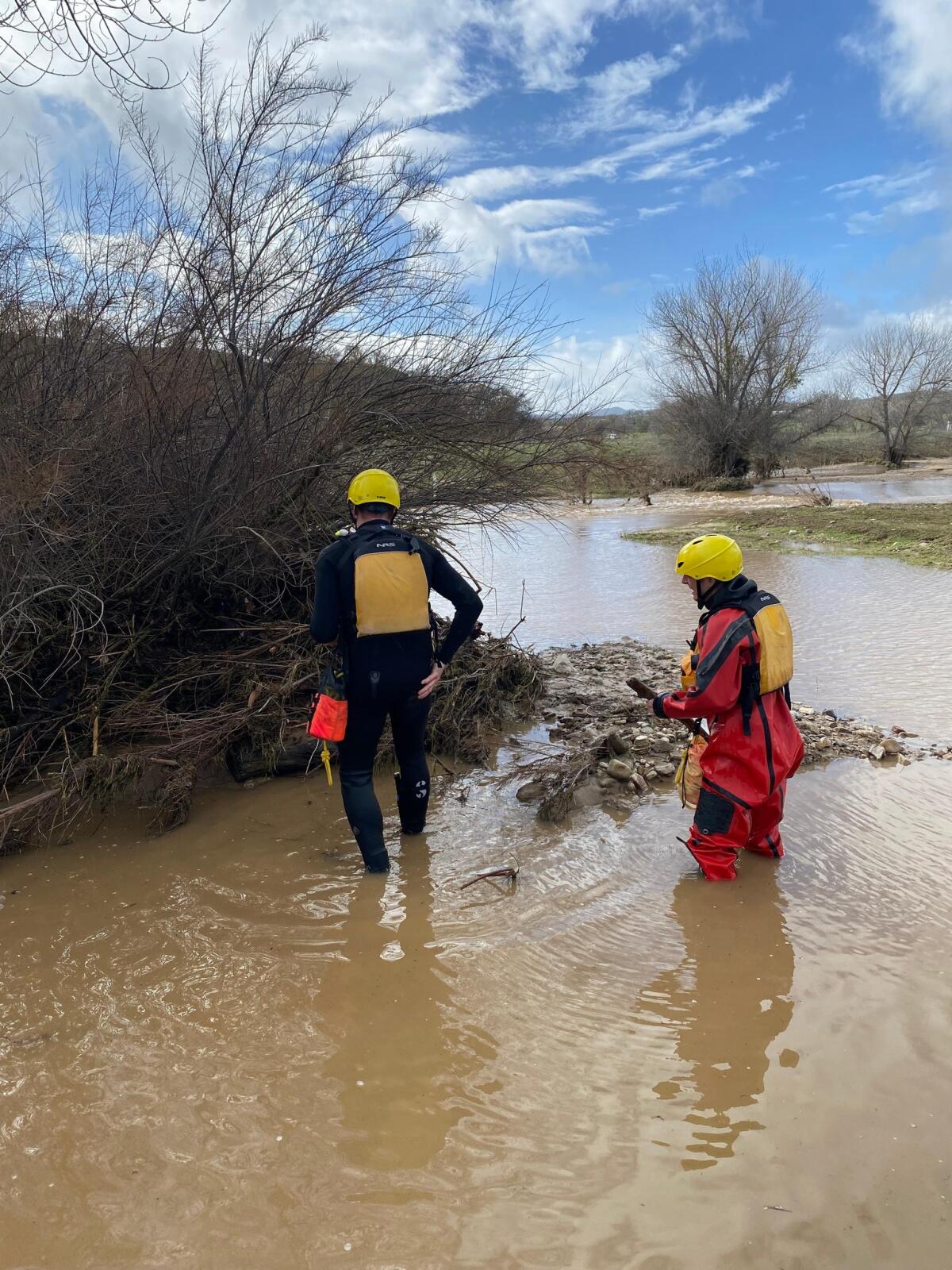 People in helmets and waders search a riverbed