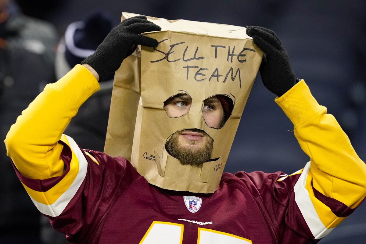 A Washington Commanders fan wears a bag over his head with the message "Sell the Team."