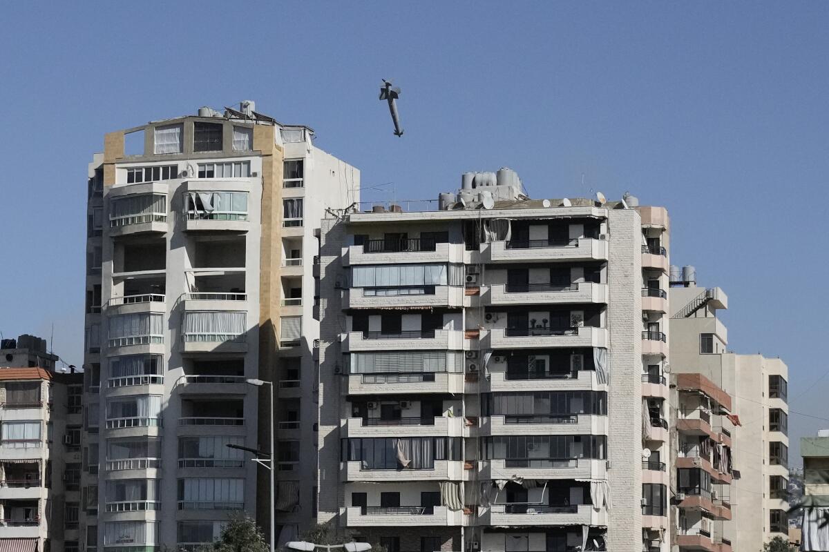 A missile soars toward multistory buildings with balconies.