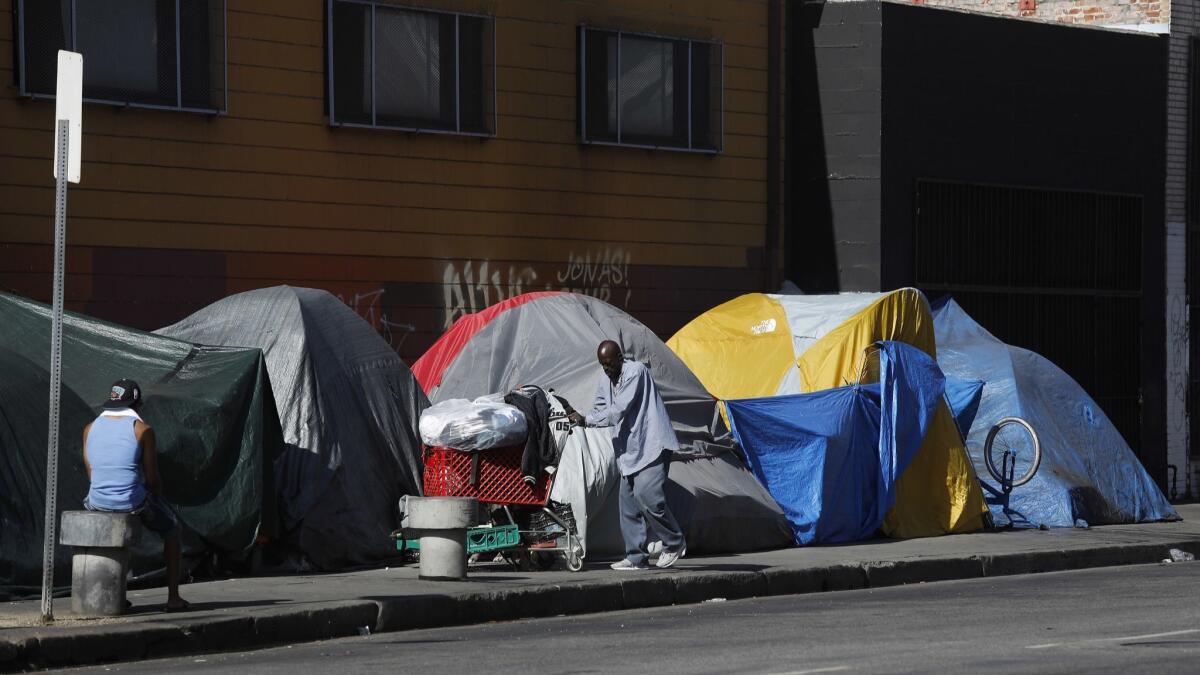A homeless man pushes his shopping cart to outside his tent located on 7th Street near Stanford Avenue in downtown Los Angeles. An outbreak of typhus has been linked to overcrowding and homelessness in the area.
