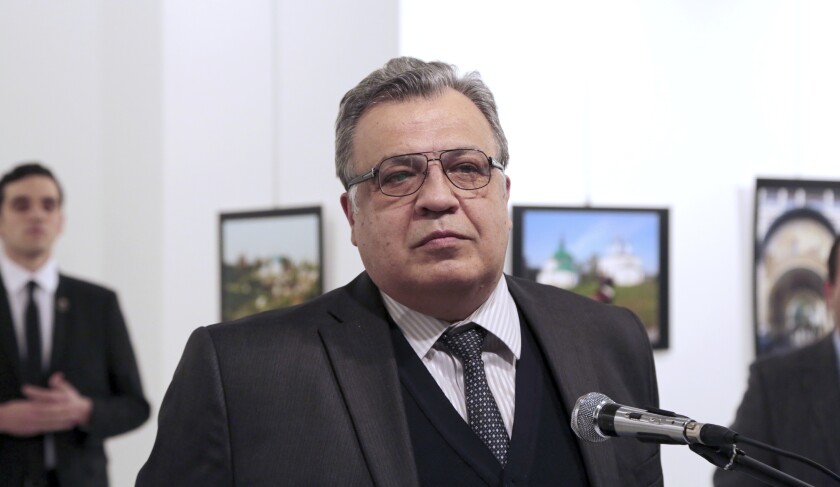 FILE - In this Monday, Dec. 19, 2016 file photo, Andrei Karlov, then Russian Ambassador to Turkey, pauses during a speech at a photo exhibition in Ankara, moments before Mevlut Mert Altintas, background left, opened fire on him and killed him. Altintas was killed by police shortly afterwards. A Turkish Court on Tuesday, March 9, 2021 sentenced five people to life prison terms over the assassination of Karlov. Turkish prosecutors concluded that a network led by U.S.-based Muslim cleric Fethullah Gulen was behind Karlov's slaying and charged 28 people, including Gulen, over the killing. (AP Photo/Burhan Ozbilici, File)