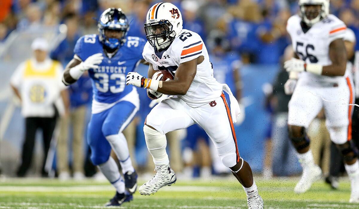 Auburn's Peyton Barber runs from a Kentucky defender during a game on Thursday.