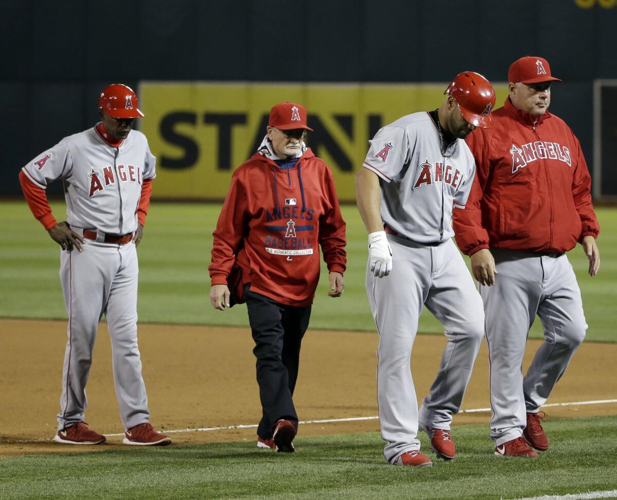 Angels first baseman Albert Pujols, alongside Manager Mike Scioscia, right, grabs his left leg as he leaves the game with a hamstring injury.