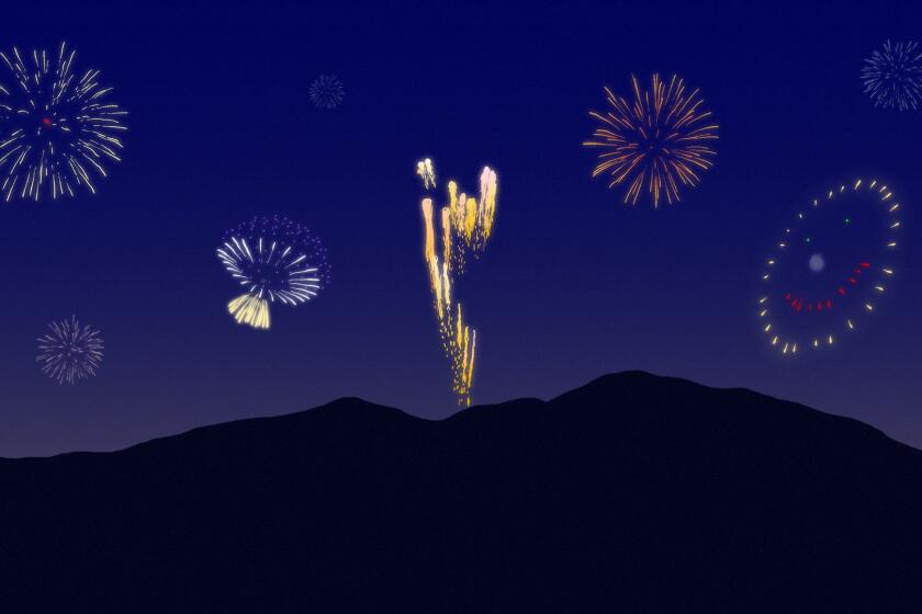 A variety of fireworks exploding in a sky behind a mountain silhouette.
