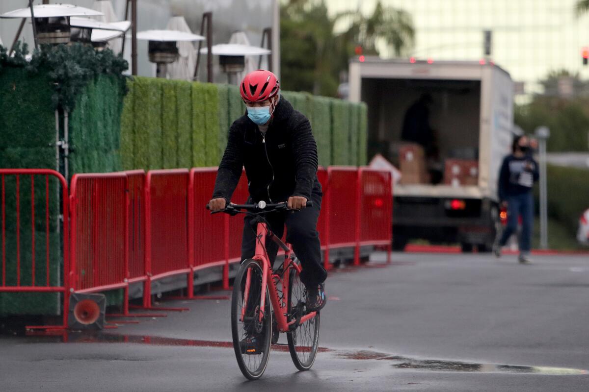 A man rides on his bike through the parking lot at South Coast Plaza on Tuesday in Costa Mesa. 