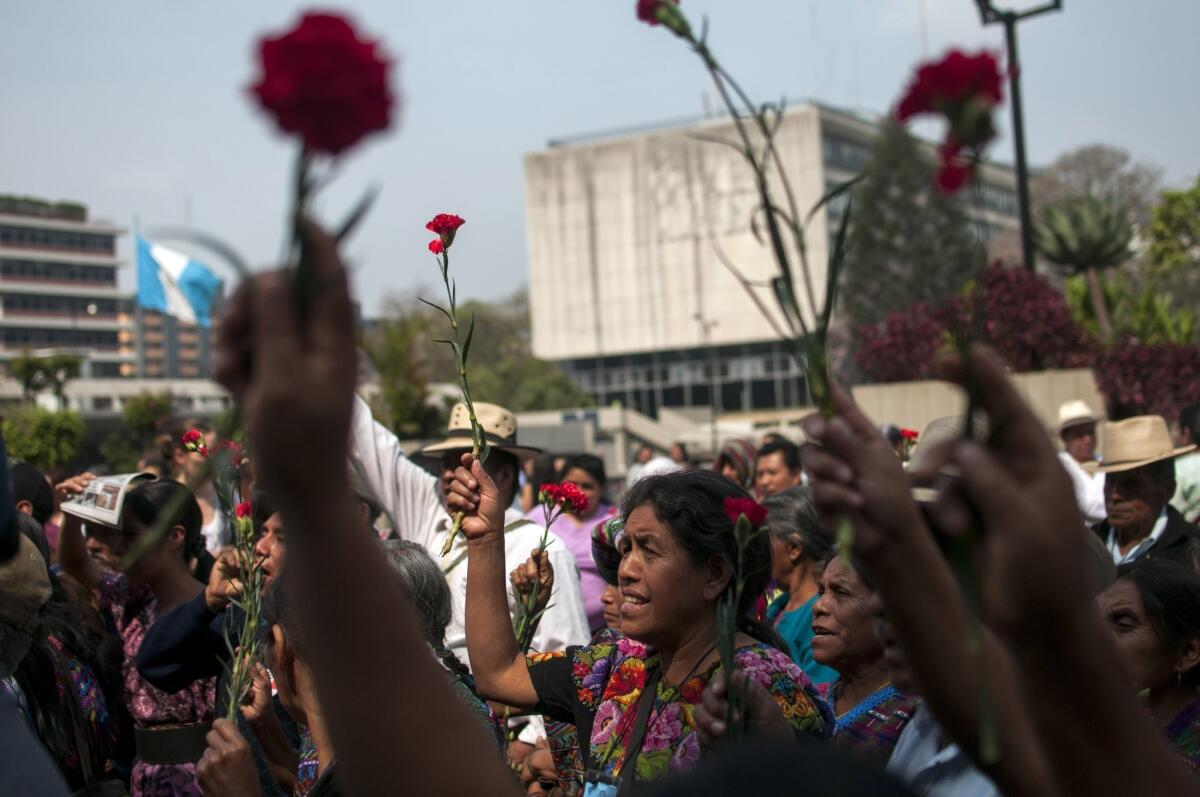 Ixil indigenous women hold up flowers outside court in Guatemala City, Friday, April 19, 2013.