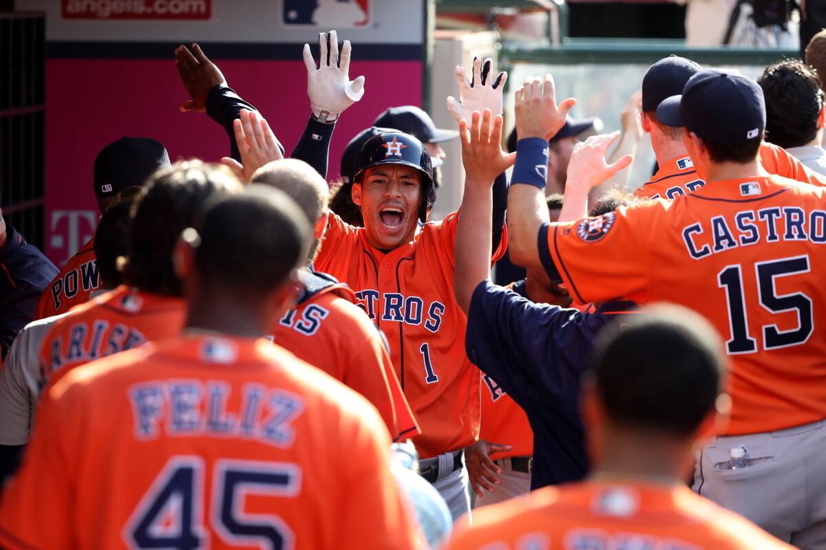 Astros shortstop Carlos Correa (1) is congratulated in the dugout after hitting a three-run home run in the 13th inning to put Houston ahead of the Angels.