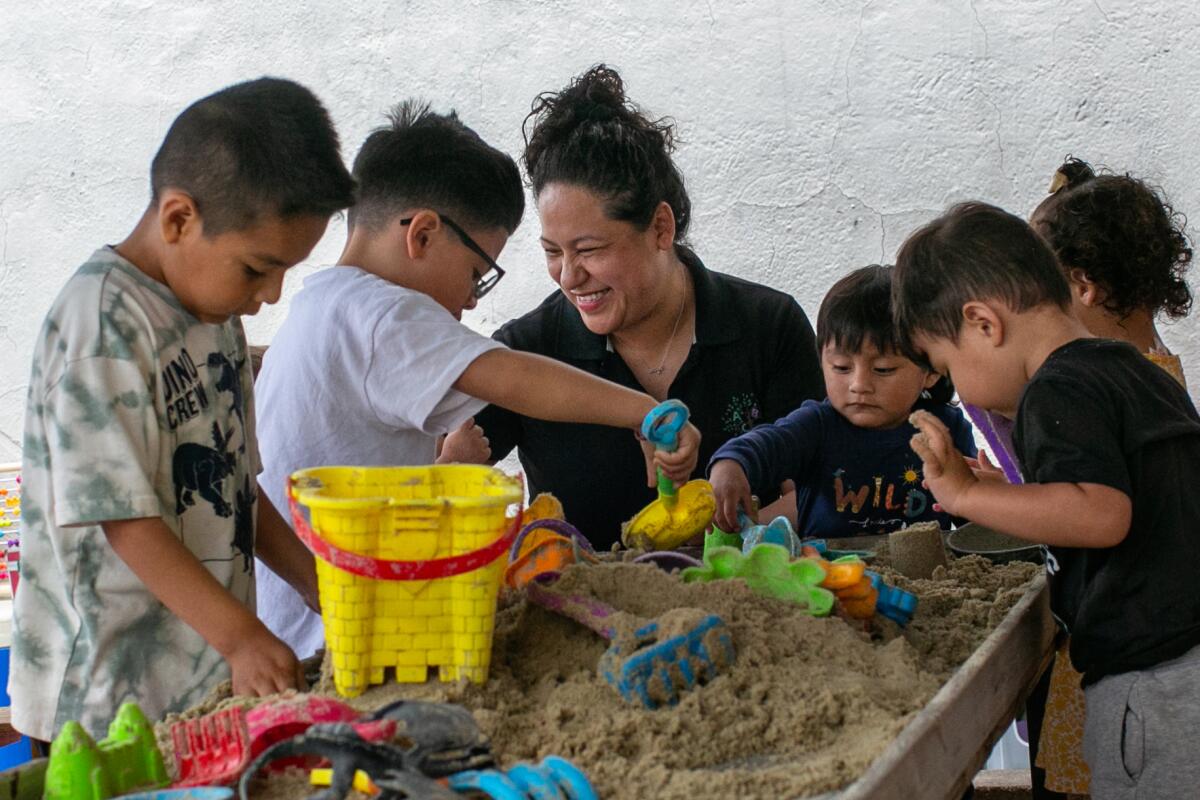 Adriana Lorenzo keeps an eye on her students as they play in a sandbox at her Boyle Heights home day care center.