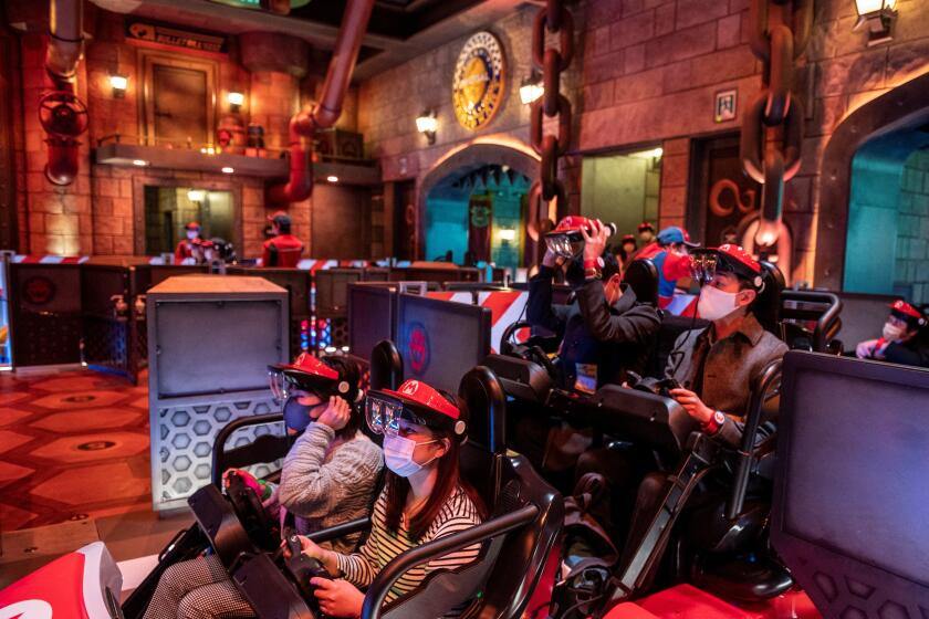 In this picture taken on March 17, 2021, fans of Universal Studios Japan wear themed augmented reality goggles for the "Mario Kart" ride during a media preview of the Super Nintendo World at Universal Studios Japan in Osaka. (Photo by Philip FONG / AFP) (Photo by PHILIP FONG/AFP via Getty Images)